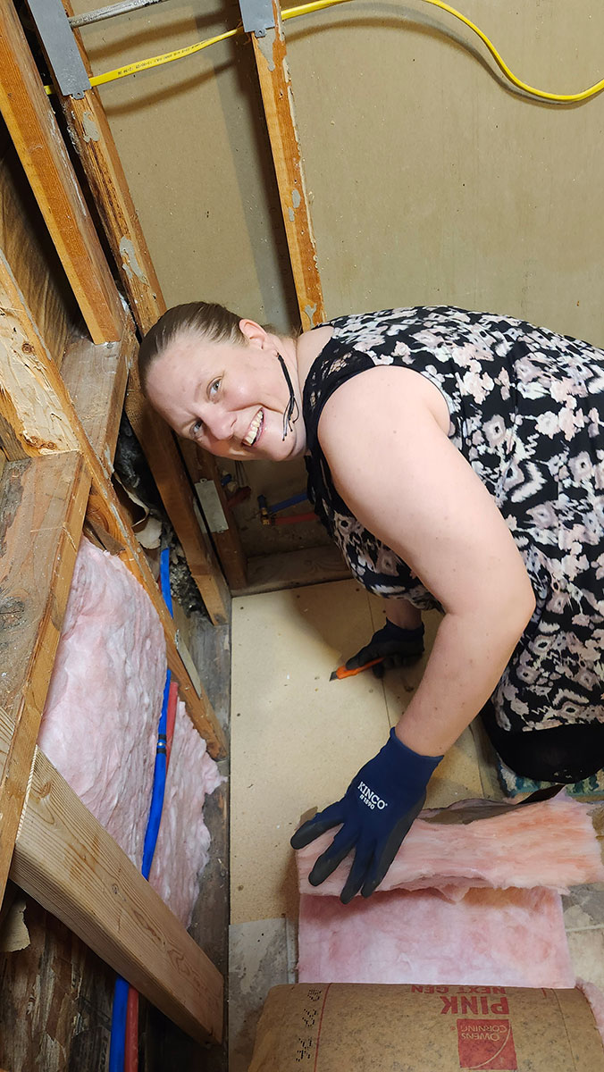 Tiffany working with insulation during the Blue Cabin renovation
